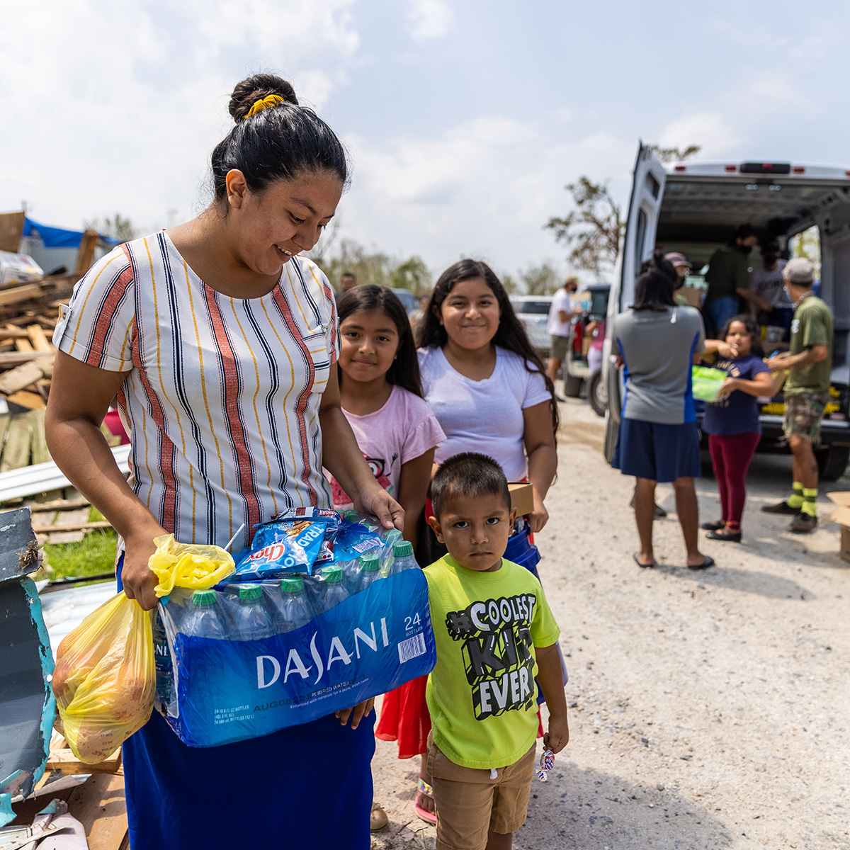 Water distribution in New Orleans. A woman with her kids holding a pack of water.