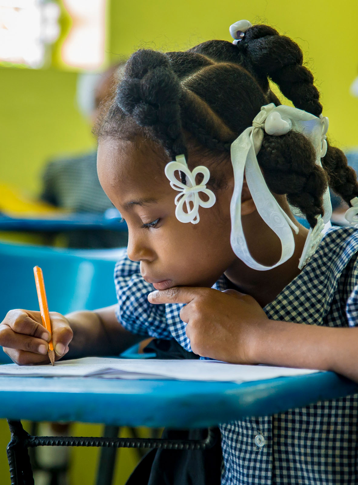 A young Haitian student sitting at her desk, working on homework.