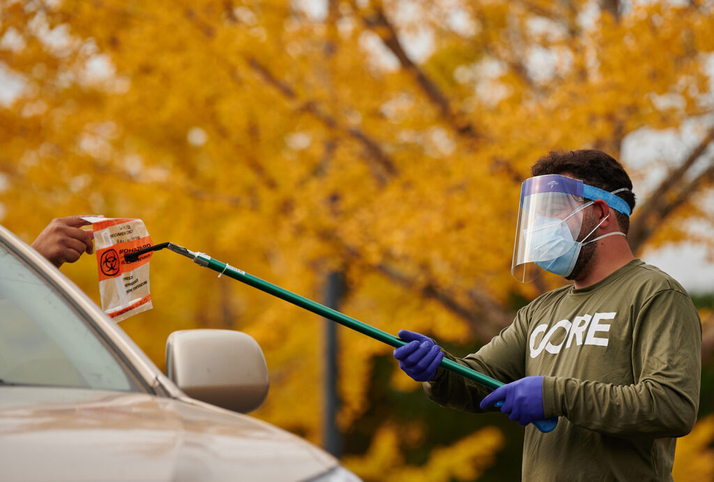 CORE staff in PPE administering a COVID test to someone in their car.