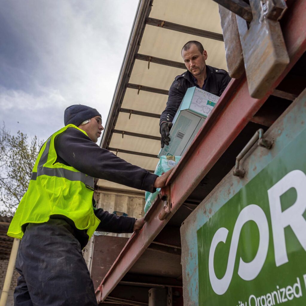 Man standing in the bed of a CORE truck hands construction materials to another man.