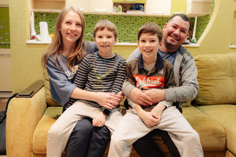 A Ukrainian family smiles for a photo inside their new apartment.