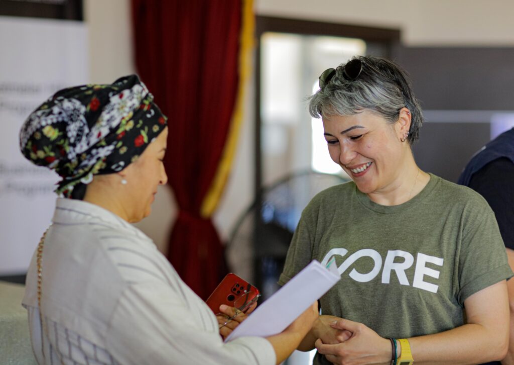 Local CORE staff in Turkey smiling while speaking with a woman businessowner