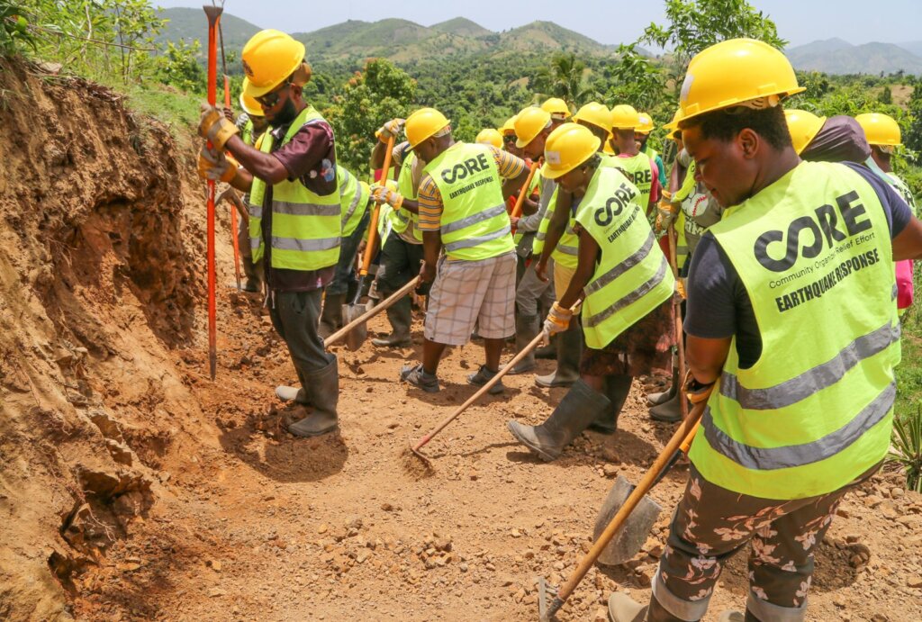 People clearing dirt and rubble on a mountainside