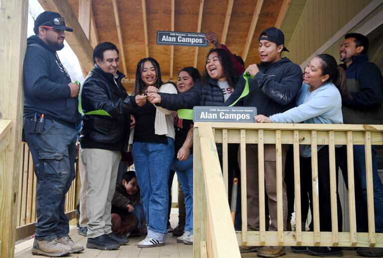 A group of residents at a ribbon cutting ceremony to celebrate them getting back into their rebuilt homes.