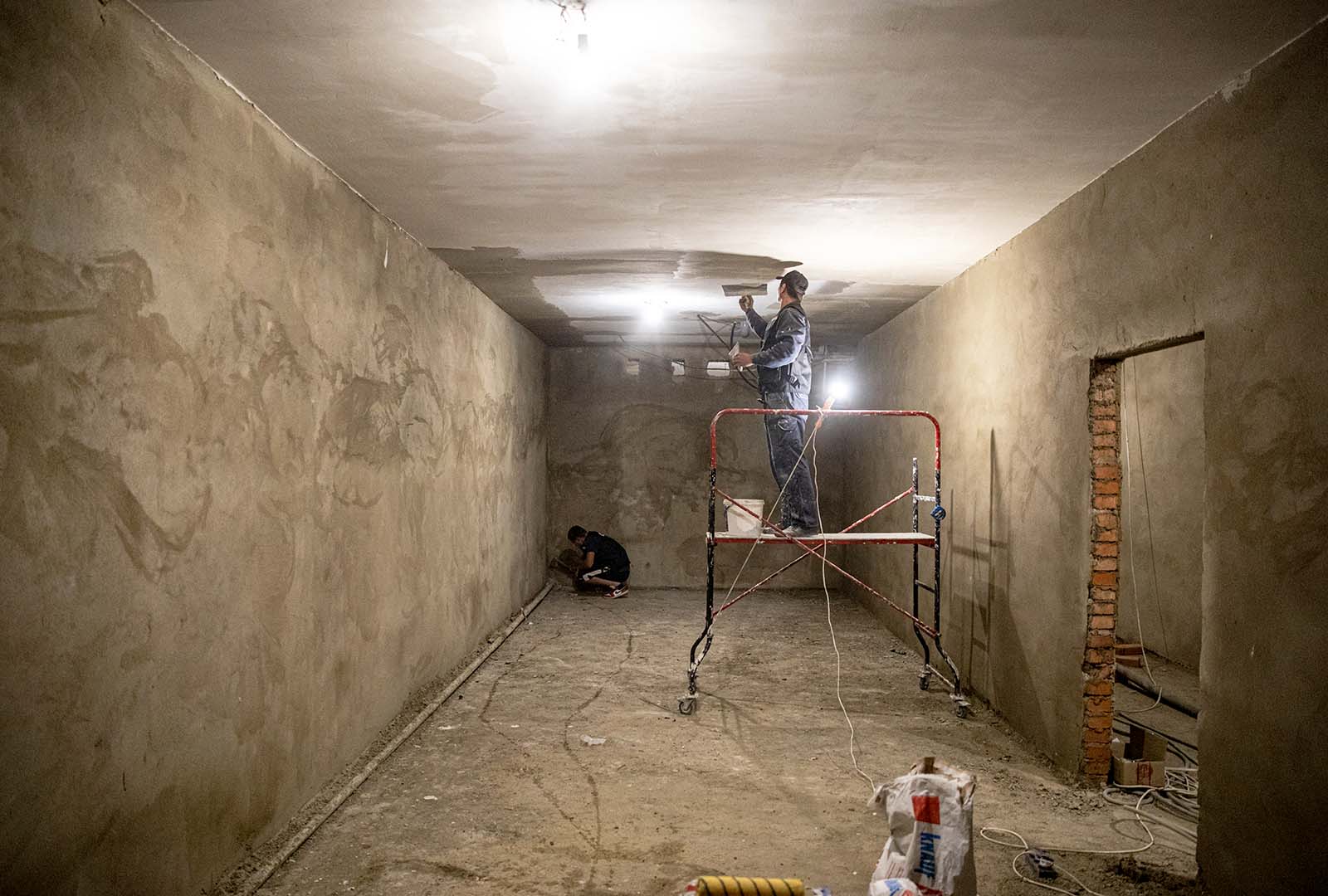 A man stands on scaffolding as he works on bomb shelter renovations in Ukraine.