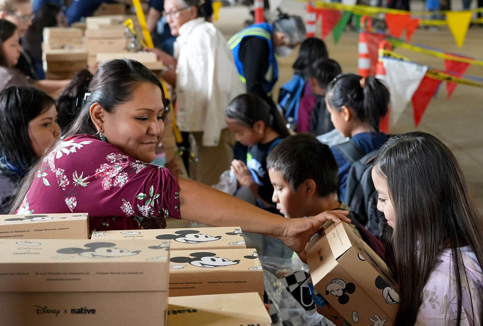 A woman hand a child a pair of donated shoes at a distribution event on Navajo Nation.