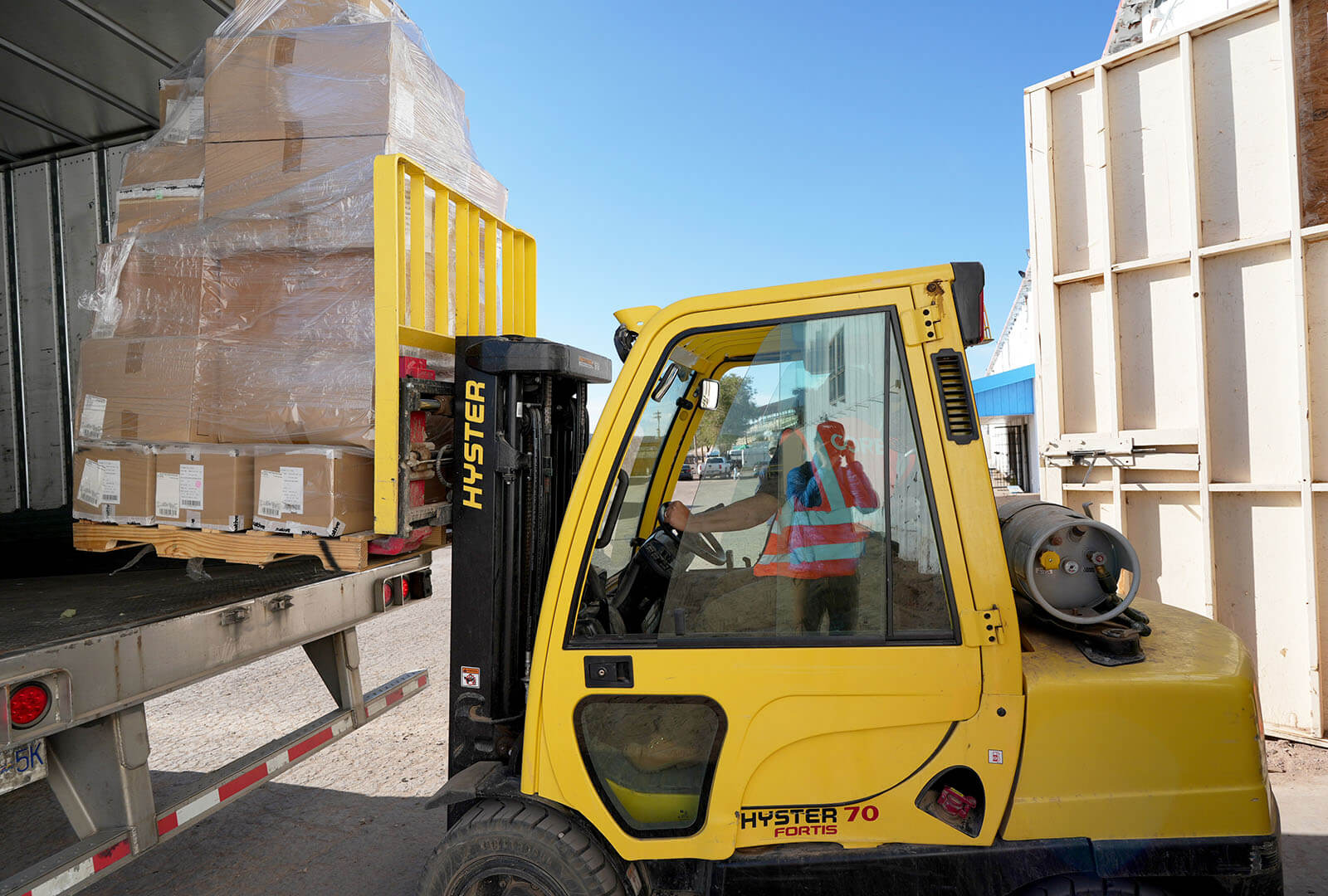 CORE team member unloads boxes of shoes using a fork lift.