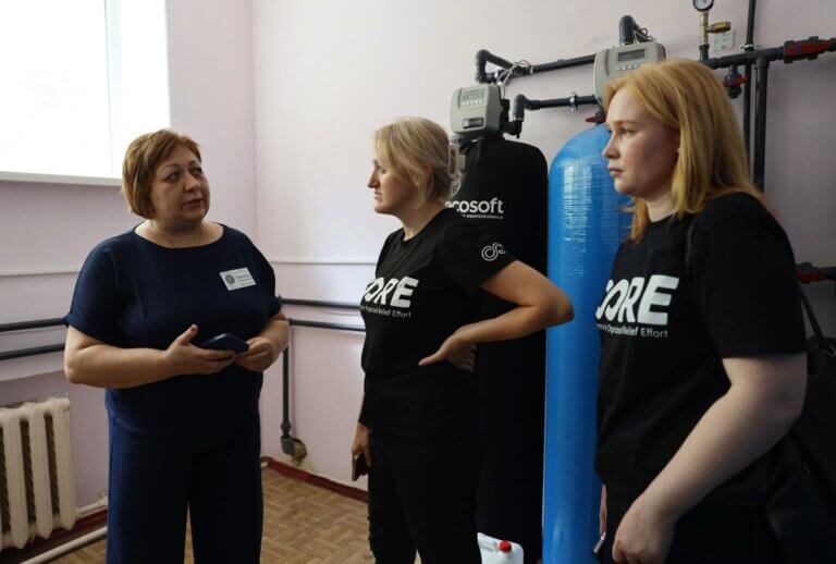CORE staff speaking in front of water tanks and water filtration system - ukraine 2