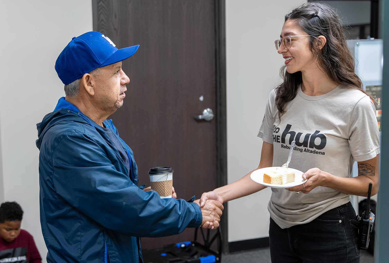 Two people shake hands at the opening of The Hub