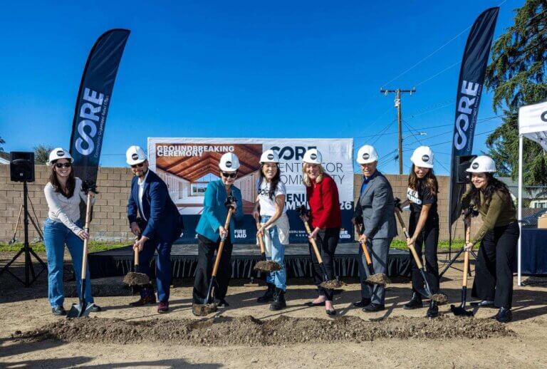 A group of people wearing hardhats shovel dirt at a groundbreaking ceremony in Altadena.