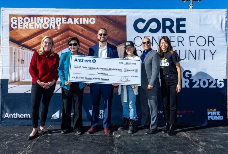 A group of people stand on a stage to receive a large check.