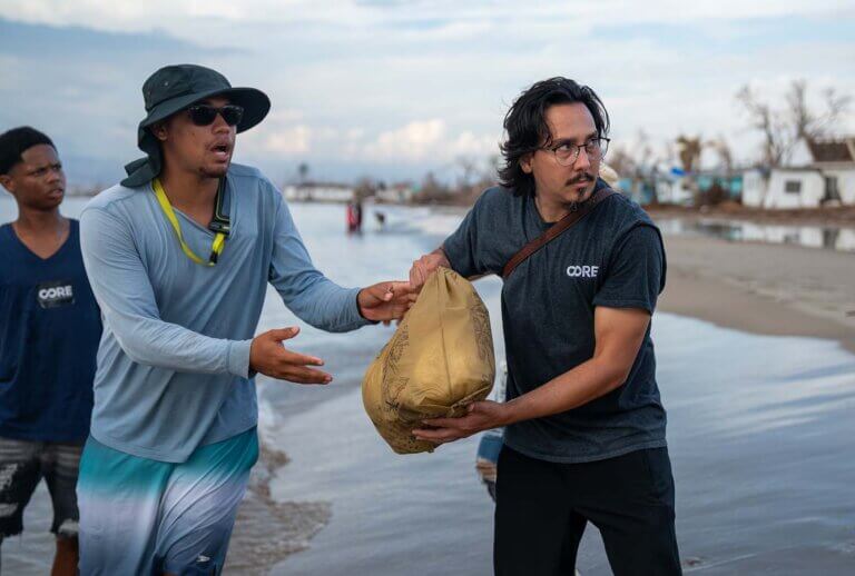Staff standing in water, bringing supplies ashore in Jamaica.
