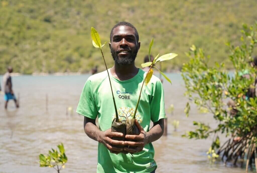 man in CORE shirt holding a mangrove sprout