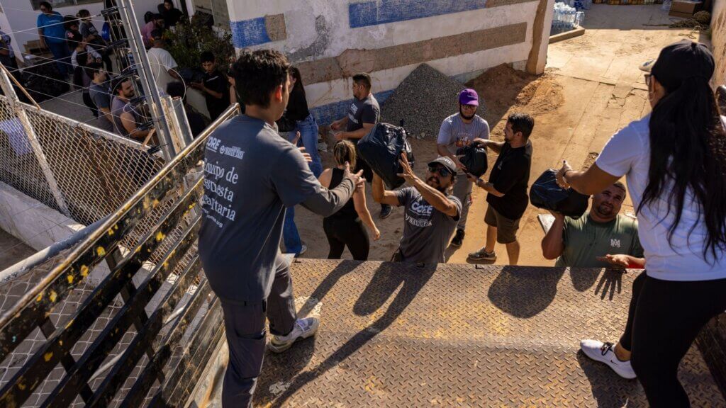 men and women loading bags of items into a truck