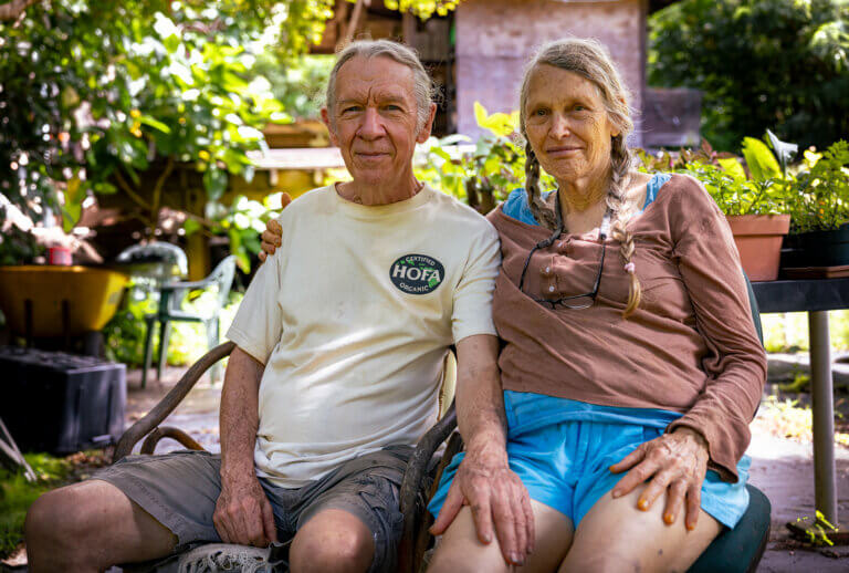 Portrait photo of a couple sitting down on a bench on Molokai.