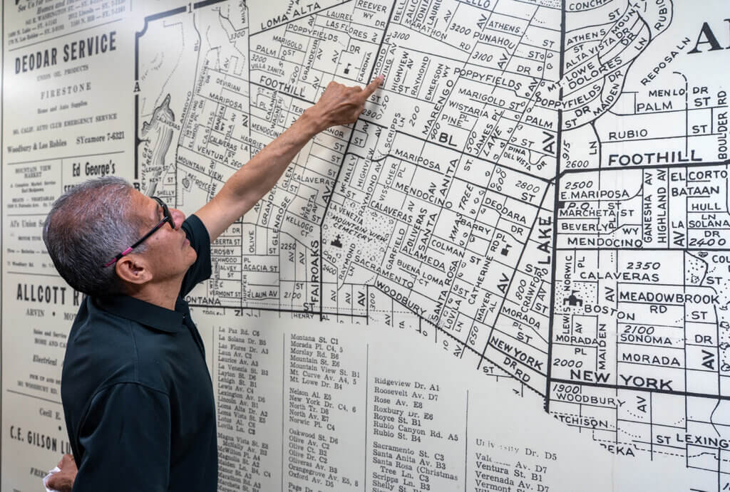 A man points at a map of Altadena on a wall to where his home was located.
