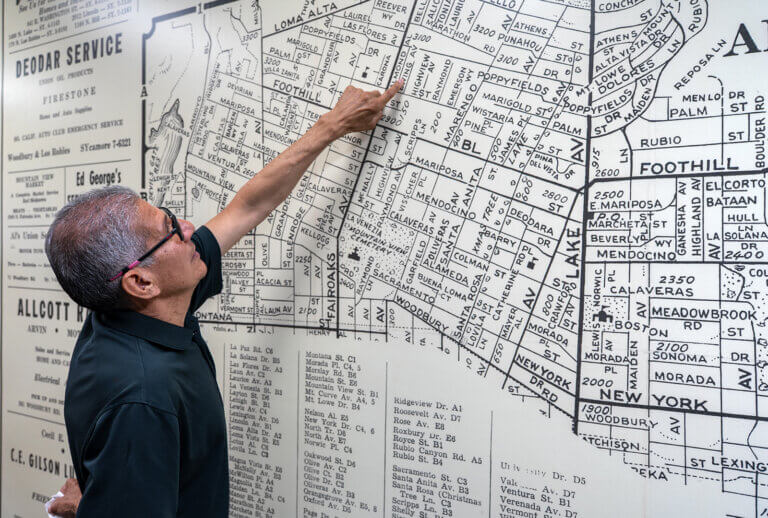 A man points at a map of Altadena on a wall to where his home was located.