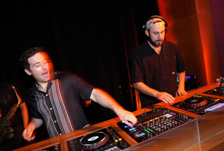 DJs, Two Friends, mixing a set behind a booth at CORE's Afterglow event in Los Angeles